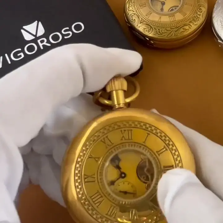 Hands in white gloves opening the hunter case of a gold VIGOROSO pocket watch to show its open-heart dial